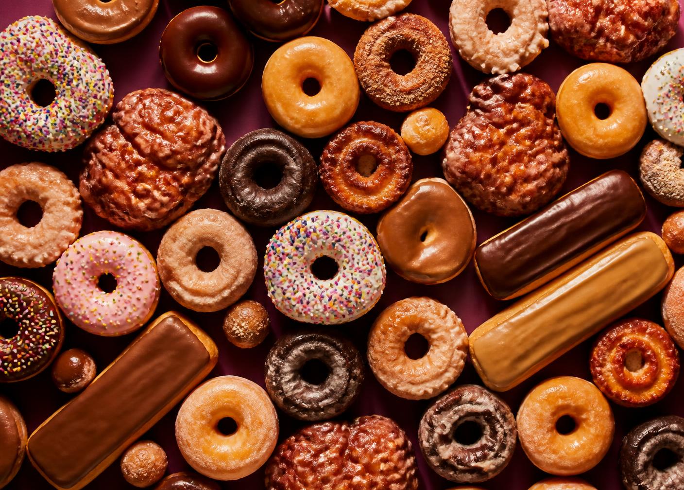 Overhead tray of glazed donuts, apple fritters and chocolate bars at Golden Donuts